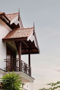 a white house with brown roof and balcony