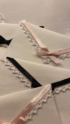 four envelopes with lace and ribbons on them sitting on top of eachother