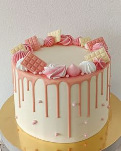 a pink and white cake with icing on top is sitting on a gold plate