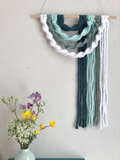 a vase filled with flowers next to a wall hanging