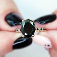 a woman's hands holding a black diamond ring