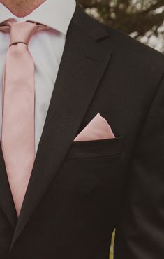 a man in a suit with a pink tie and pocket square on his lapel