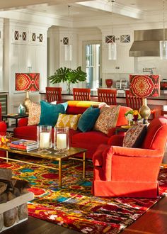 a living room filled with red couches and colorful rugs on top of a hard wood floor