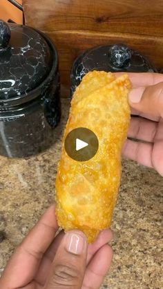 a person holding up a piece of food in front of some crockpots