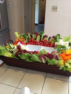 a tray filled with lettuce, carrots and radishes on top of a kitchen floor