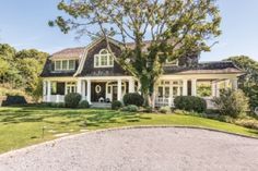 a large house sitting in the middle of a lush green field with lots of trees