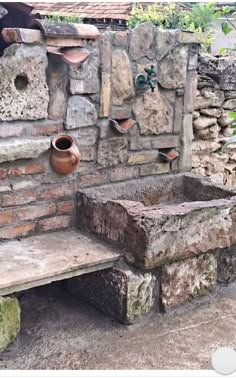 a stone bench sitting next to a brick wall and potted plant on top of it