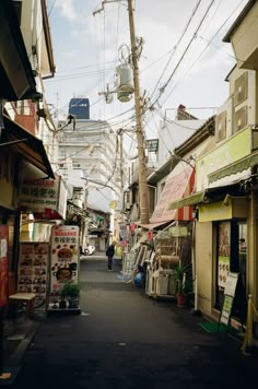 an alley way with lots of shops on both sides and telephone wires above the buildings