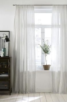 a white curtain in front of a window with a potted plant