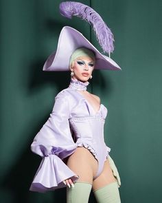 a barbie doll is dressed in purple and wearing a hat with feathers on the top