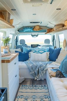 the interior of a camper van with blue and white pillows on the couches