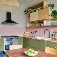 a bowl of green apples sitting on top of a wooden table next to a stove