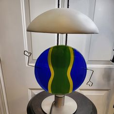 a blue and green lamp sitting on top of a black table next to a white door