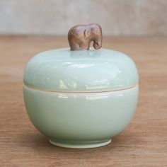 an elephant figurine is sitting on top of a bowl that has it's lid open