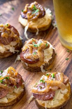 small appetizers are arranged on a wooden board next to a glass of beer