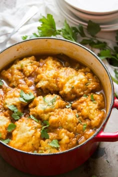 a red pot filled with food and garnished with cilantro on top