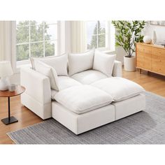 a white couch sitting on top of a hard wood floor next to a table and lamp