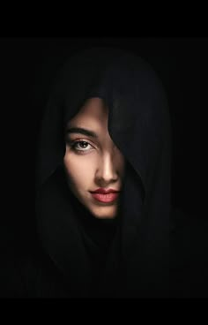 a woman wearing a black hood and red lipstick is looking at the camera with an intense look on her face