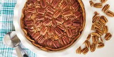 a pecan pie on a white plate with spoons next to it