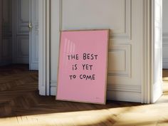 a pink sign that says the best is yet to come in front of an open door