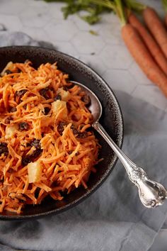 a bowl filled with carrots and raisins on top of a gray cloth