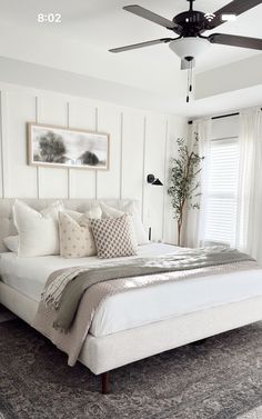 a white bed sitting in a bedroom on top of a wooden dresser next to a window