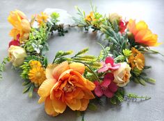 a wreath made out of flowers and greenery on top of a gray tablecloth