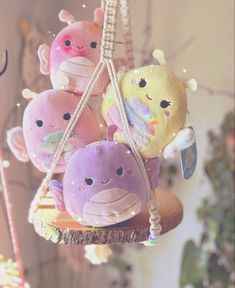 a group of stuffed animals sitting on top of a wooden swing suspended from a ceiling