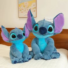 two stuffed animals sitting on top of a bed