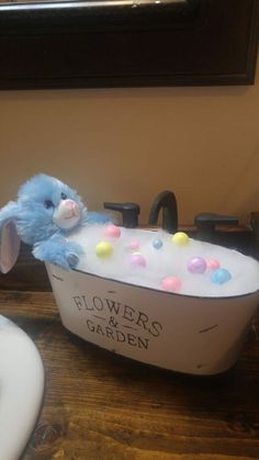 a blue stuffed animal in a bathtub with flowers and garden written on the side