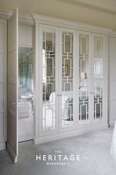 an elegant bedroom with mirrored doors and white furniture