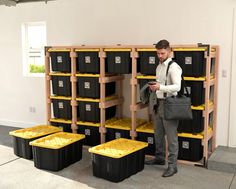 a man standing in front of stacks of black and yellow bins, looking at his cell phone