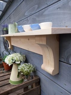 a shelf on the side of a building with vases and flowers sitting on it