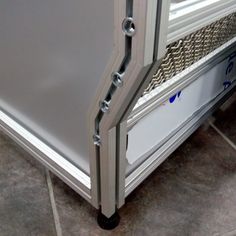 an open refrigerator door on the floor in front of a tile floor with gray tiles