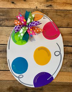 a painted plate with colorful polka dots on it and a bow hanging from the top