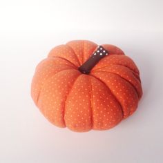 an orange polka dot pumpkin sitting on top of a white table