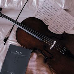 an old violin and book laying on a bed