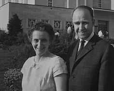 a man and woman standing in front of a building