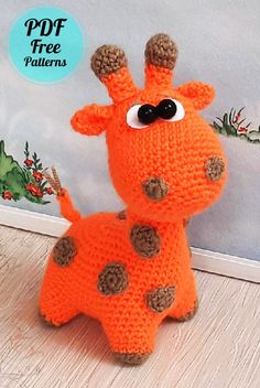 a knitted giraffe sitting on top of a wooden floor next to a wall