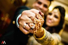 a man and woman holding hands with henna tattoos on their fingers while posing for the camera