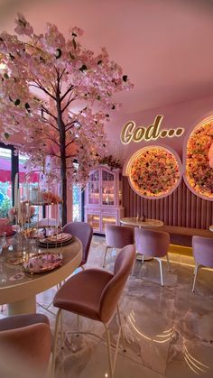 the inside of a restaurant with pink chairs and flowers on the wall behind the tables