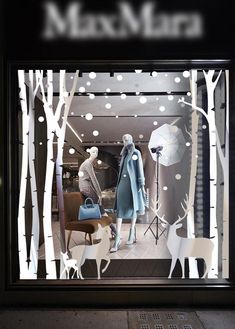 a window display with white trees and deer