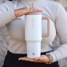 a woman holding a white tumbler cup in her hands