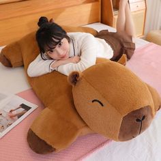 a woman laying on top of a large teddy bear pillow with her arms around the head