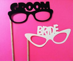 two black and white photo props with the words bride and groom written on them in front of a pink background