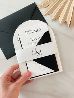 a person holding up a black and white wedding card with the word details printed on it