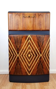 an art deco cabinet with wood and metal trimmings on the front, sitting on a hard wood floor