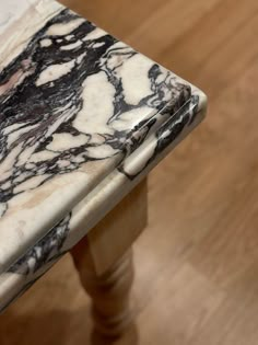 a marble topped table with wooden legs on a hard wood floor