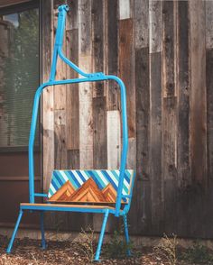 a blue metal chair sitting in front of a wooden building