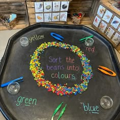 a black tray with writing on it that says sort the beans into colours and blue